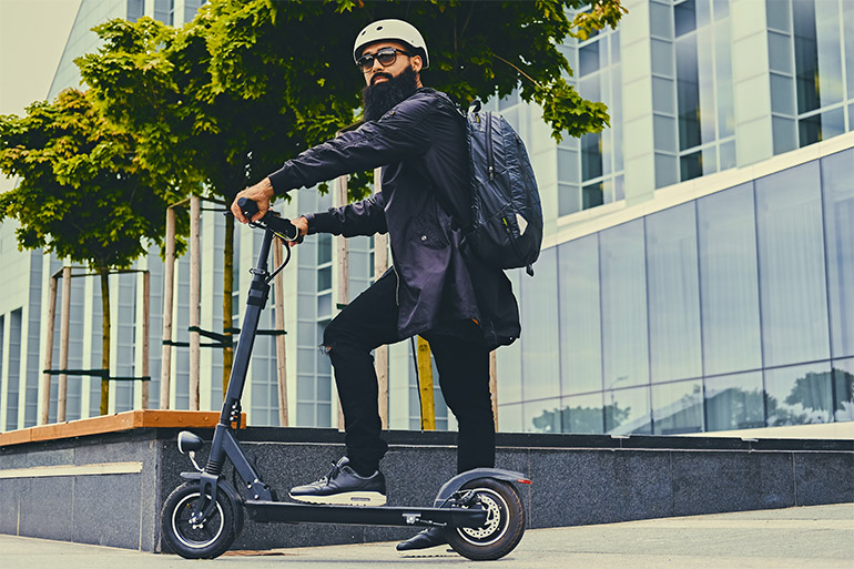 A person stands on a scooter.