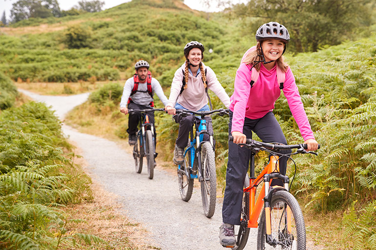 Three people ride a bike on a path.