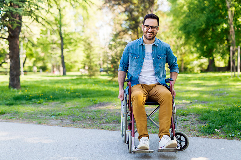 A person sits in a wheelchair on a path.