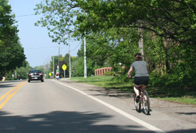 A bicyclists rides on the shoulder of a road.